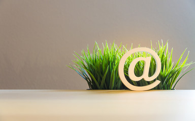 email at-sign and green grass, symbol for sustainable and environmental-friendly internet and...