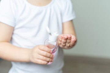 a little girl of 4 years in a white T-shirt puts a sanitizer on her hands. hand treatment in the conditions of the emulsion of coronavirus KOVID-19
