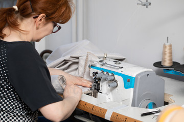 Experienced seamstress sews pillow covers on a sewing machine called overlock.