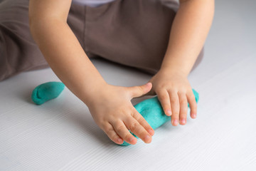 Closeup hands of preschooler child roll out dough for modeling. quarantined children's art