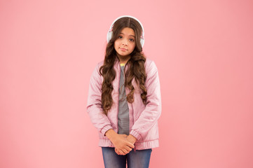 cute and shy. Need more fun. Fun and entertainment. Joining in a song. Small girl with sad look pink background. Little child hear stereo sound. Enjoying song playing in headphones