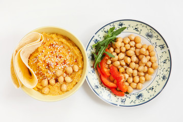 Homemade traditional hummus, vegetables, lavash in bowls. White background. Horizontal top view. ...