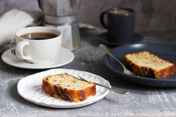 Banana muffin with candied ginger and raisins and drinks on a gray background.
