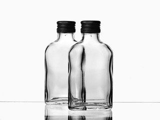 Two empty glass russian vodka bottle with black cap isolated on a white background