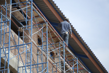 Naklejka premium construction worker is walking on temporary scaffolding not safe