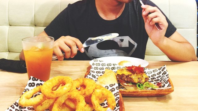 Woman Eating Burger And Onion Rings In Restaurant