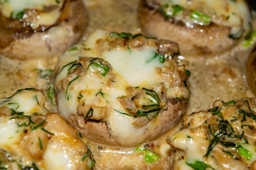 Mushrooms baked in the oven with cheese, green onions and dill. Close up.