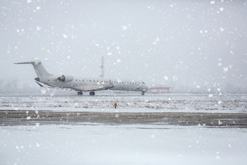 Airliner on runway in blizzard. Aircraft during taxiing on landing strip during heavy snow. Passenger plane in snow at airport.