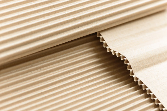 Carton or cardboard packing material. Texture of corrugated paper sheets made from cellulose. Supplies for creating boxes and packaging. Pasteboard background. Natural brown cardboard surface.