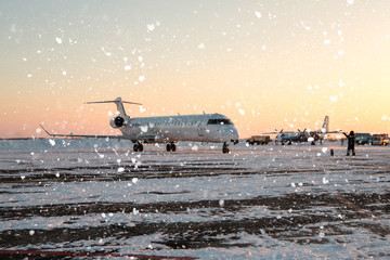 Passenger plane at airport in evening in winter. Airplane at a snowy airport in  winter evening