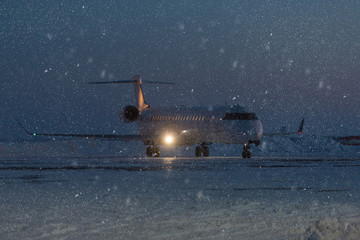Passenger plane at airport in evening in winter. Airplane at a snowy airport in  winter evening