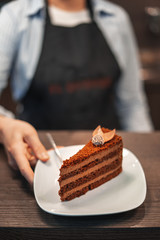 Girl pastry chef serves chocolate cake.