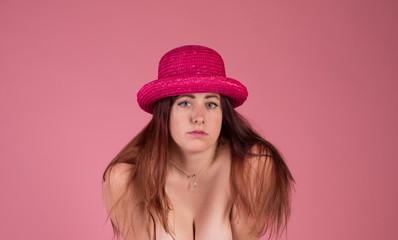 Redhead with striking blue eyes on a pink background with a pink hat