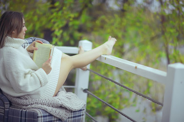 Naklejka premium green trees book girl spring, young beautiful girl reads a book on the veranda seasonal look