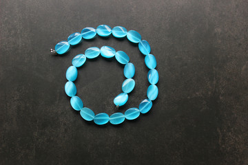 blue beads on a dark background folded in the form of a spiral