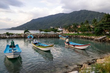 Fototapeta na wymiar Traditional fishing boats at the pier of Koh Phangan island in Thailand at sunset on a cloudy day.