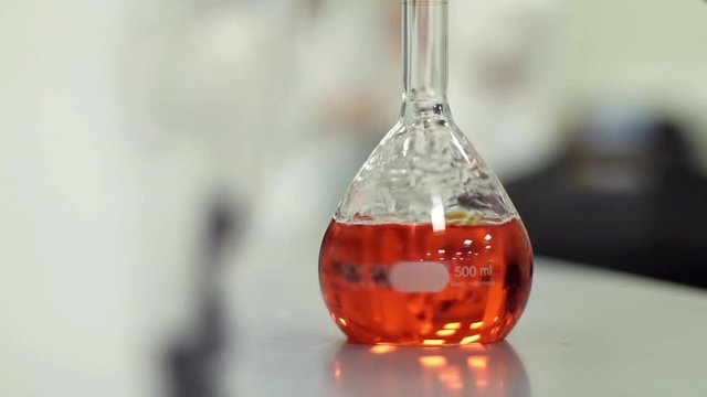 Scientist working with chemical reaction in chemistry lab. Chemical reaction in glass flask. Lab worker doing chemical experiment in laboratory