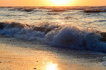 Beautiful sea waves with a lot of sea foam splash on the sandy shore. Close up