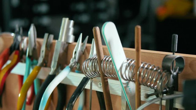Different goldsmith professional tools inside jewelry workshop. Craft jewelry making tools set. Close up, selective focus panning right and left.