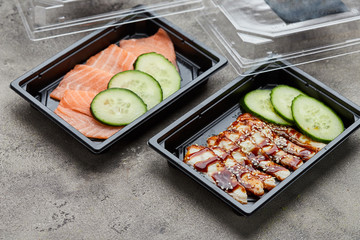 Fresh sliced salmon and smoked eel fillet with cucumber in plastic boxes ready for delivery. Wild atlantic fish