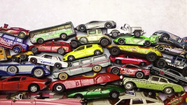 A collection of old toy cars piling up then down  transition