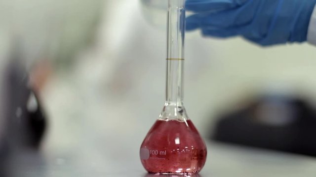Scientist working with chemical reaction in chemistry lab. Chemical reaction in glass flask. Lab worker doing chemical experiment in laboratory