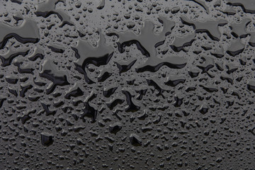 Drops of water on black texture. Selective focus.