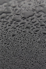 Drops of water on black texture. Selective focus.