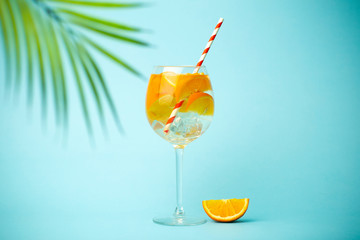Summer detox drink on a blue background. Summer cold drink with oranges and ice on an empty colored background