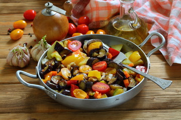 Vegetable stew with eggplant and zucchini on a wooden background