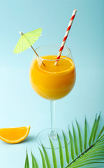 Summer drinks concept. Orange juice in a glass cup on a colored blue background. Tropical summer minimal background