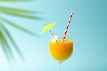 Summer drinks concept. Orange juice in a glass cup on a colored blue background. Tropical summer minimal background