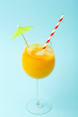 Summer drinks concept. Orange juice in a glass cup on a colored blue background. Tropical summer minimal background