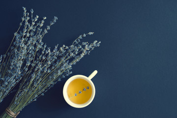 Bouquet of dry lavender and a white cup of tea on a blue surface, top view, copy space