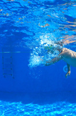 Young boy swimming in swimming pool, underwater view.