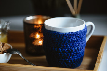 Wooden tray with tea cup and honey in a glass, cozy morning composition