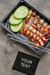 Sliced smoked eel fillet with cucumber in plastic box ready for delivery. Copy space