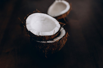 Расколотые кокосы лежат на темном деревянном фоне