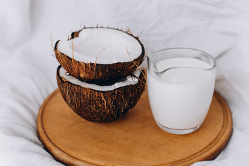Coconut milk in a glass jug. Ripe coconuts on a white background