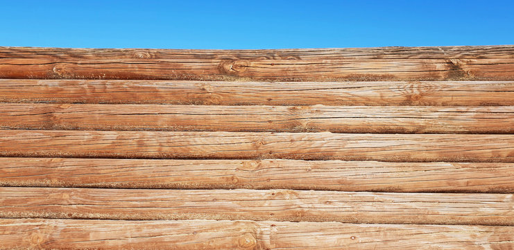 Wood background in the form of logs and blue sky. Free space for your idea.