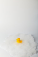 Minimalistic concept toy duck in the foam. bathing children