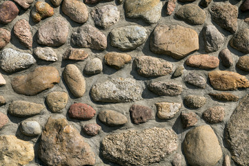A wall of pebble stones. Stones fixed with cement mortar.