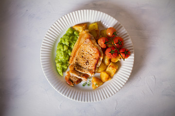 Succulent pork steak fillet with mushy peas, roast potatoes and tomatoes. Overhead horizontal image
