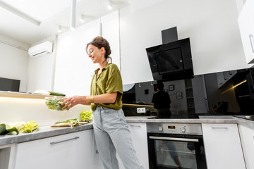 Woman cooking healthy food on the modern kitchen at home, wide intreior view