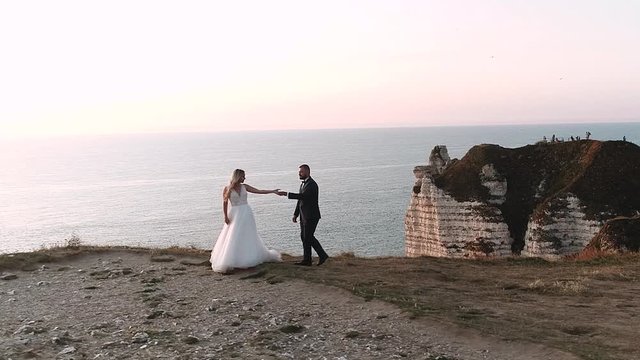 Etretat. France, Beautiful brides are photographed against nature background. Young couple walking along the waterfront. Gentle view and beautiful frames of the ocean. Slow motion.