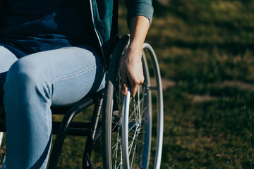 Close up of a young woman in a wheelchair while walking in a park on a sunny day. Recovery and...