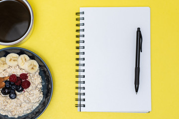 notepad with coffee and oatmeal blueberry banana bowl ready to start the day