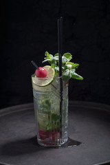 close-up, advertising shot of a light alcoholic cocktail, with a sprig of mint, icing sugar, with decorative grape berry. In a rustic style, on a dark background.