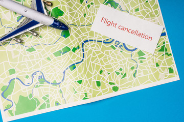 Top view of card with flight cancellation with toy plane on map isolated on blue