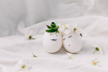 Funny easter eggs. Couple in love. Easter composition on white fabric background.